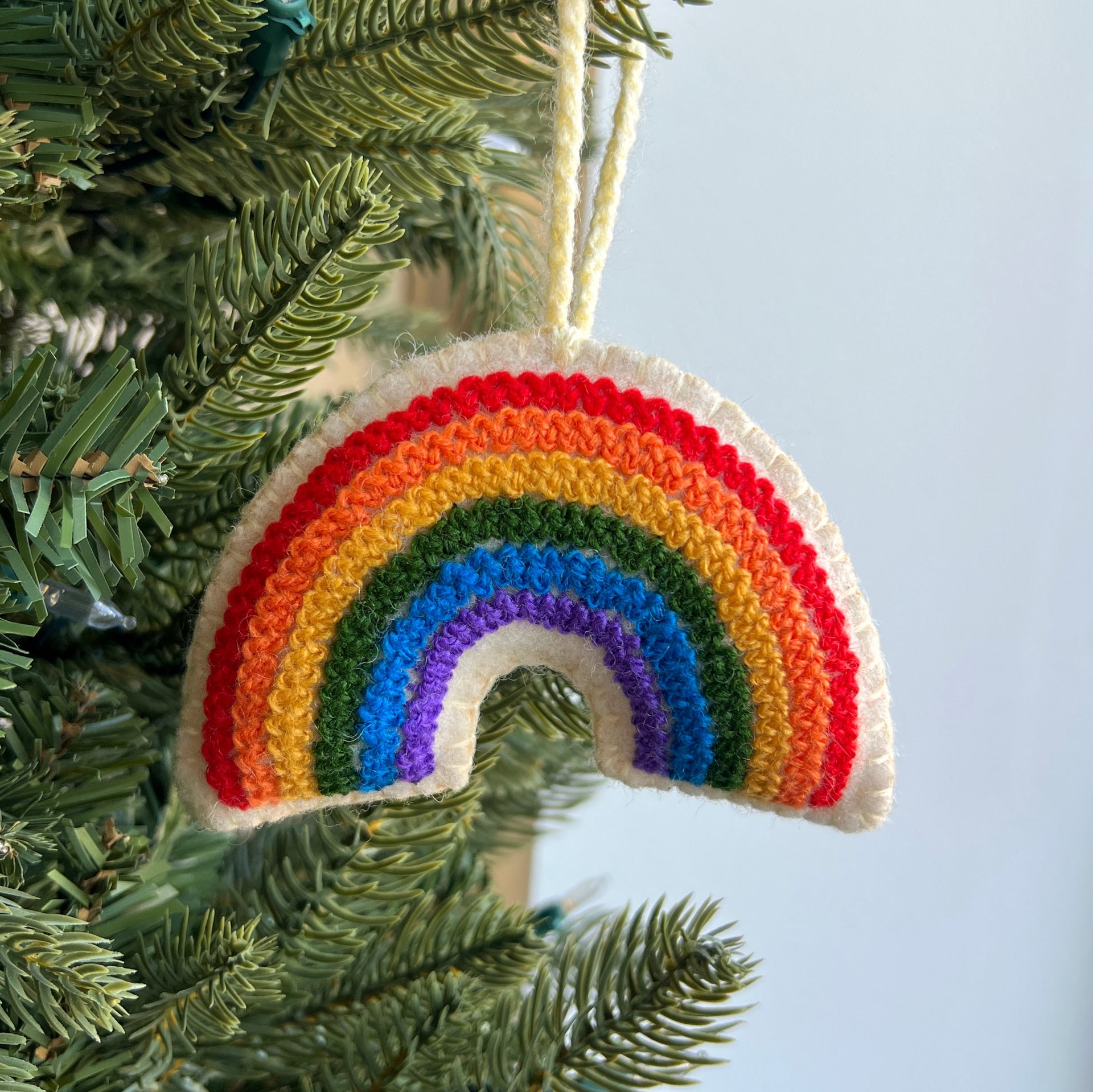 embroidered wool rainbow ornament hanging on Christmas tree