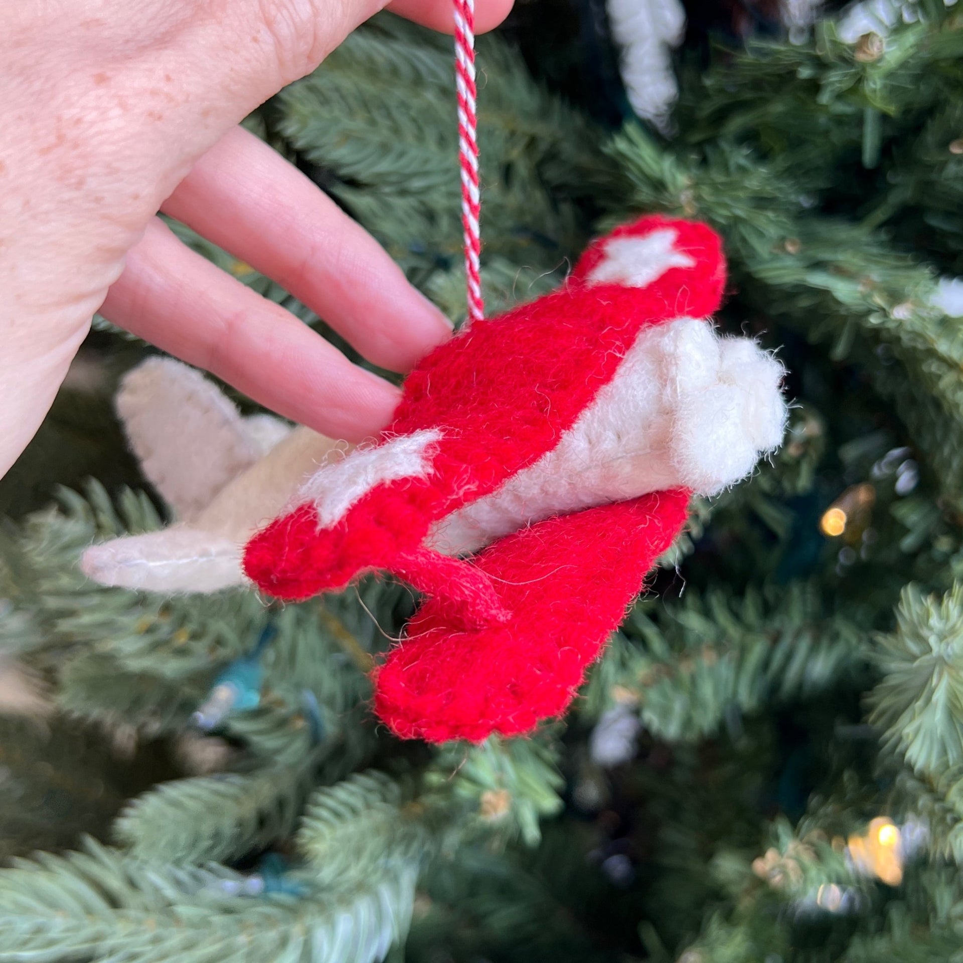 Biplane Christmas Ornament held in front of tree felt fair trade handmade Nepal