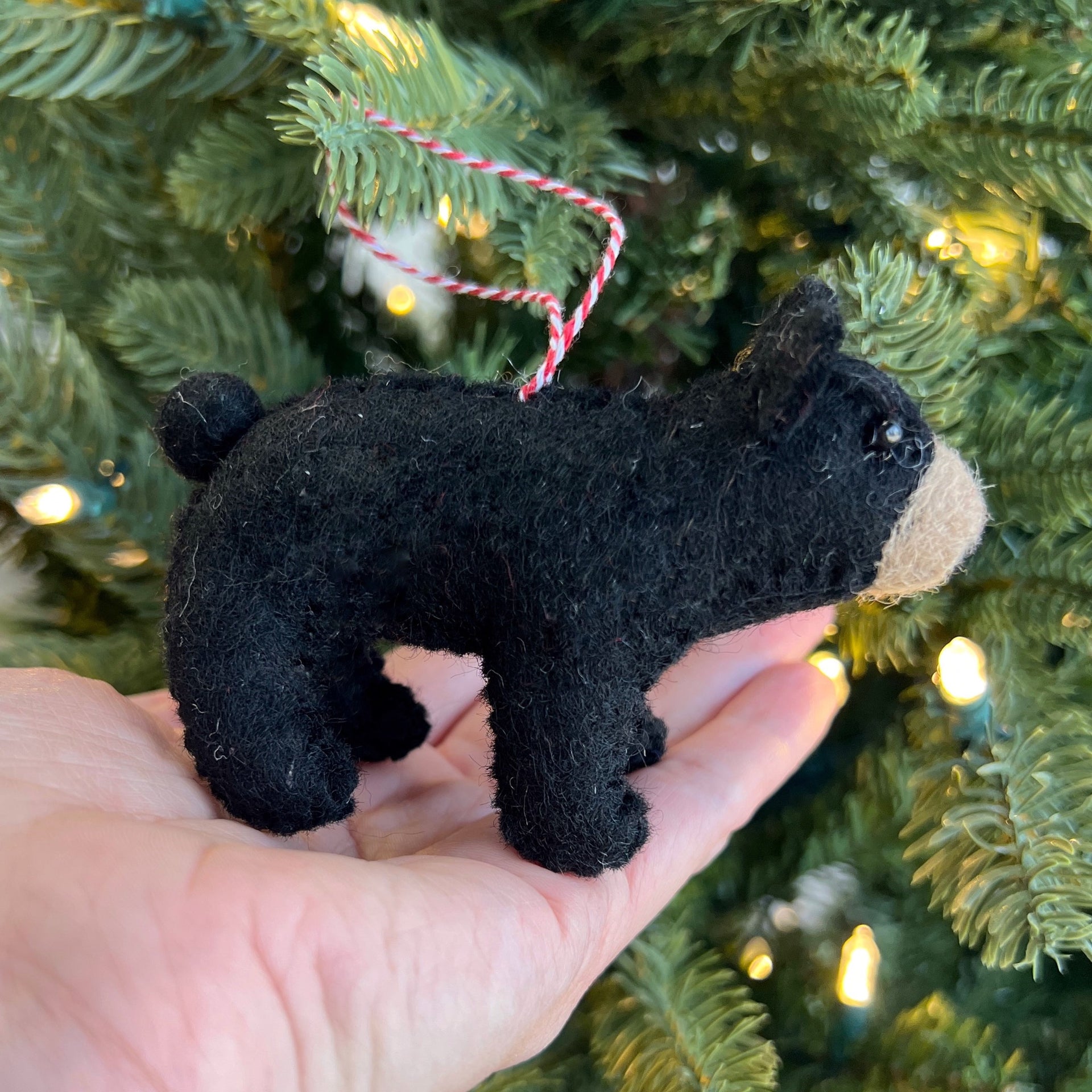 Fair trade handmade black bear ornament held by Christmas tree