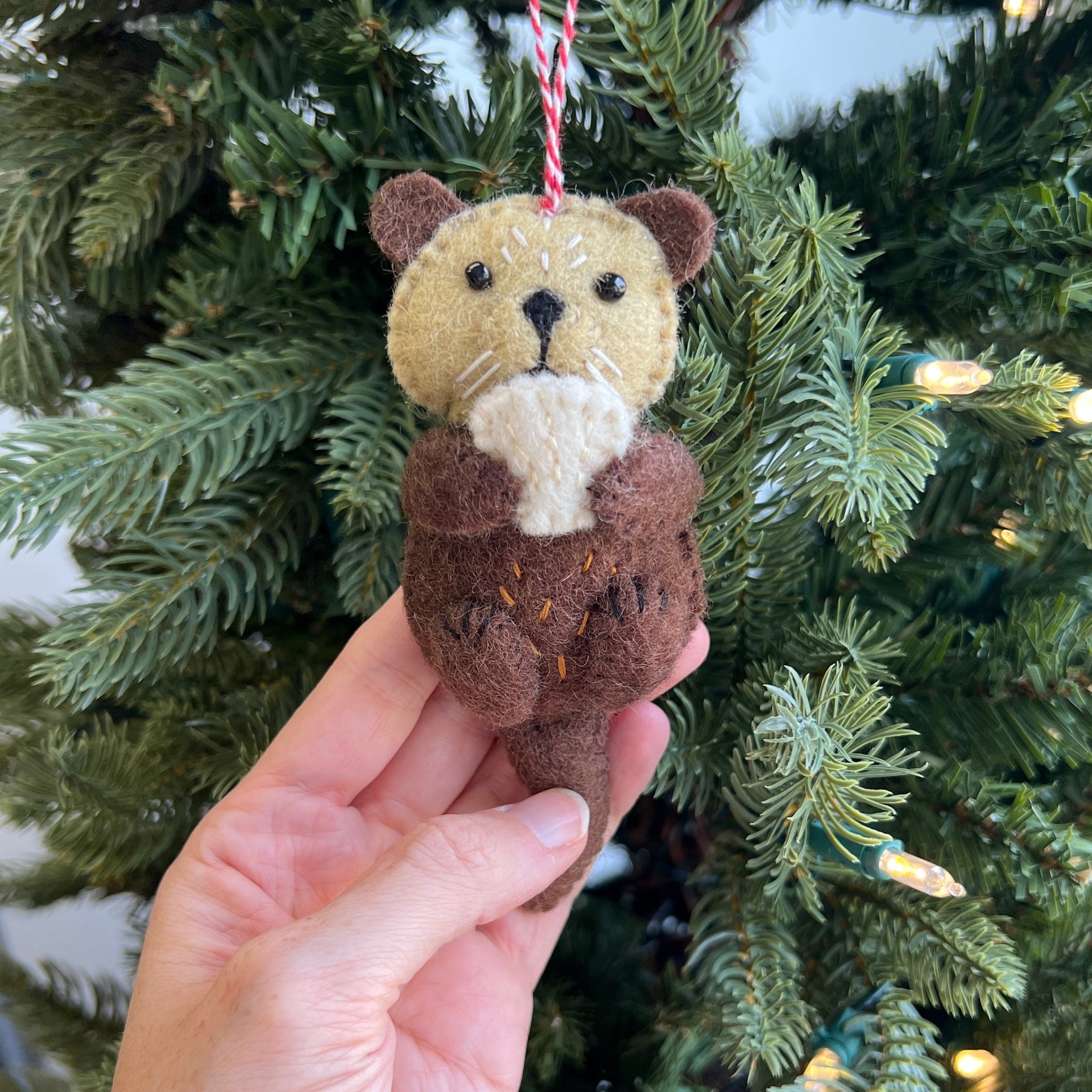 Adorable Sea Otter Felt Christmas Ornament being held on a Christmas Tree
