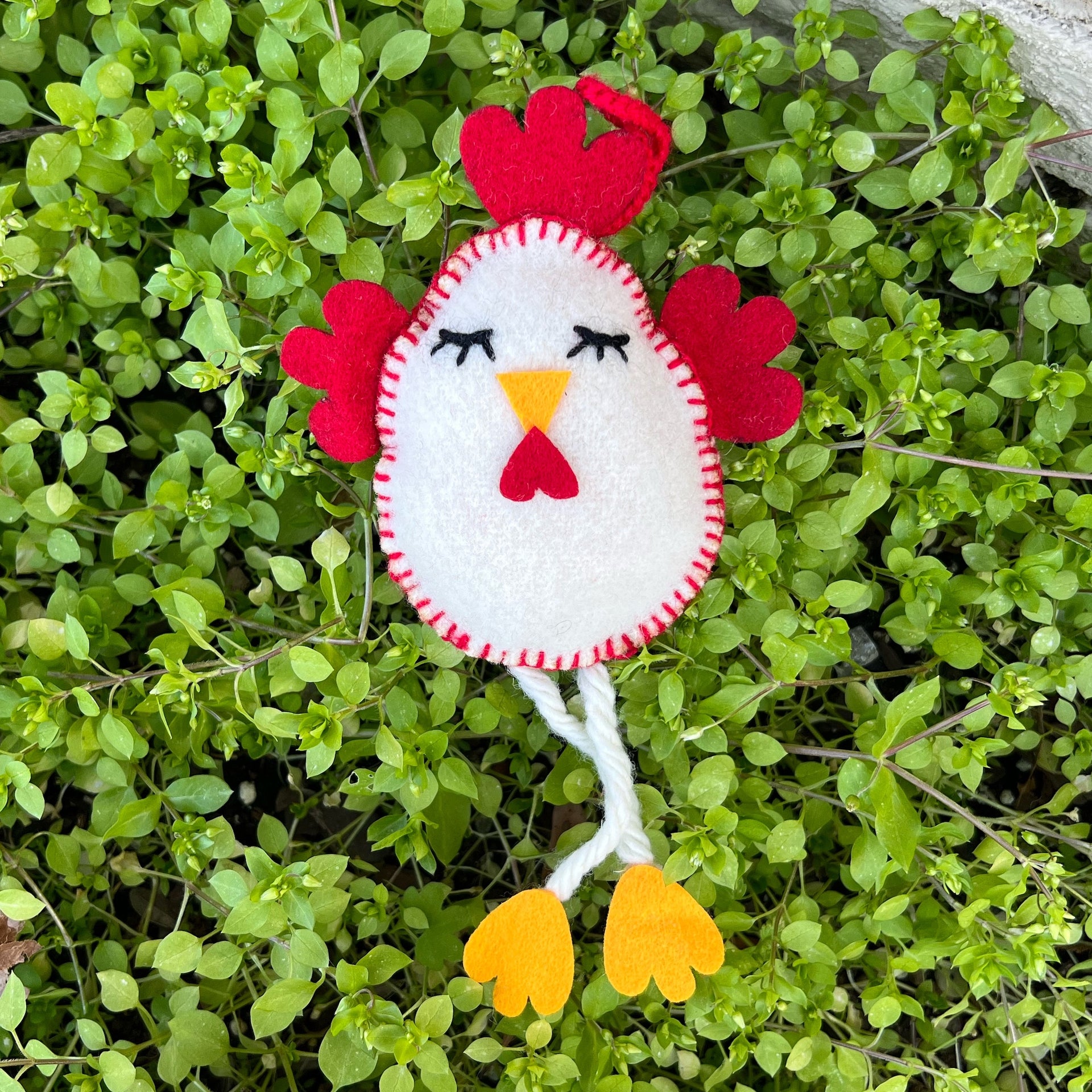 Handmade Chicken Egg Ornament with dangle legs outside on grass