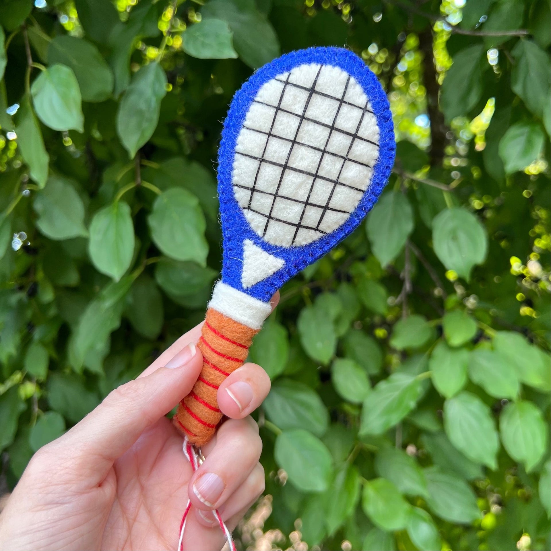 hand holding Ornaments 4 Orphans handmade tennis racquet Christmas ornament outside
