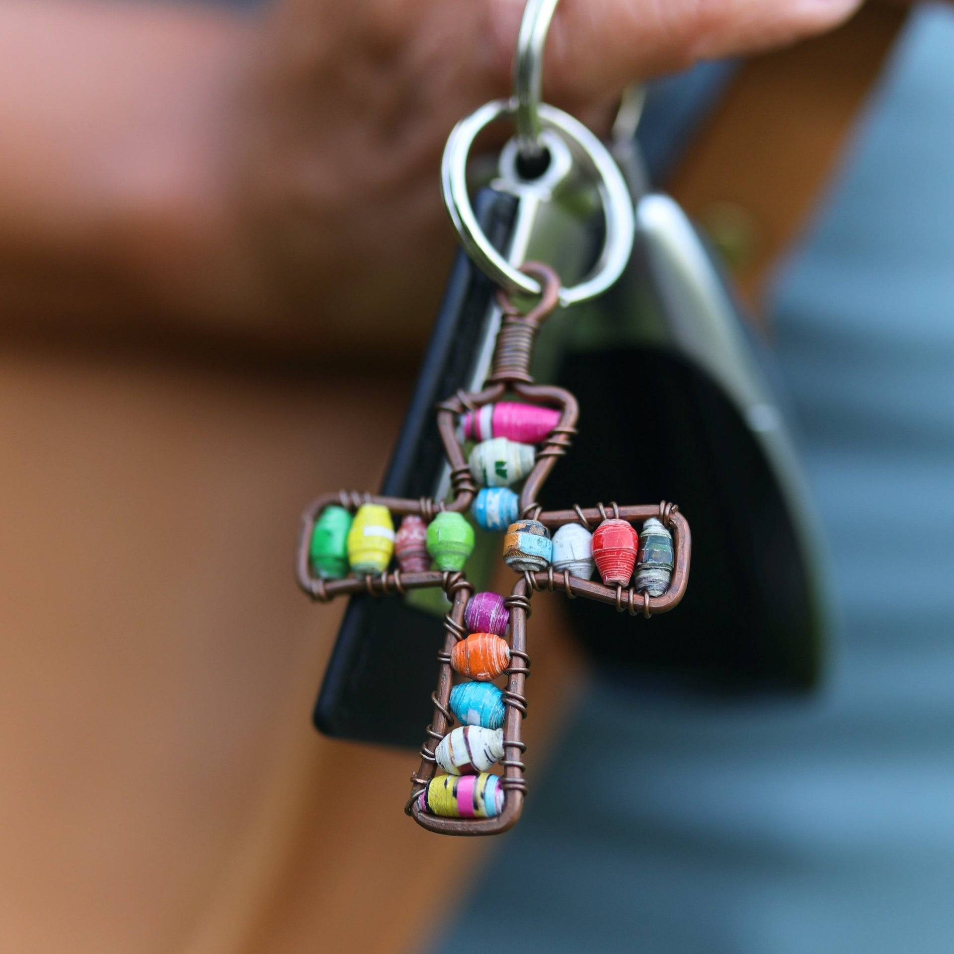 Handmade multicolor paper bead cross keychain hanging on keys