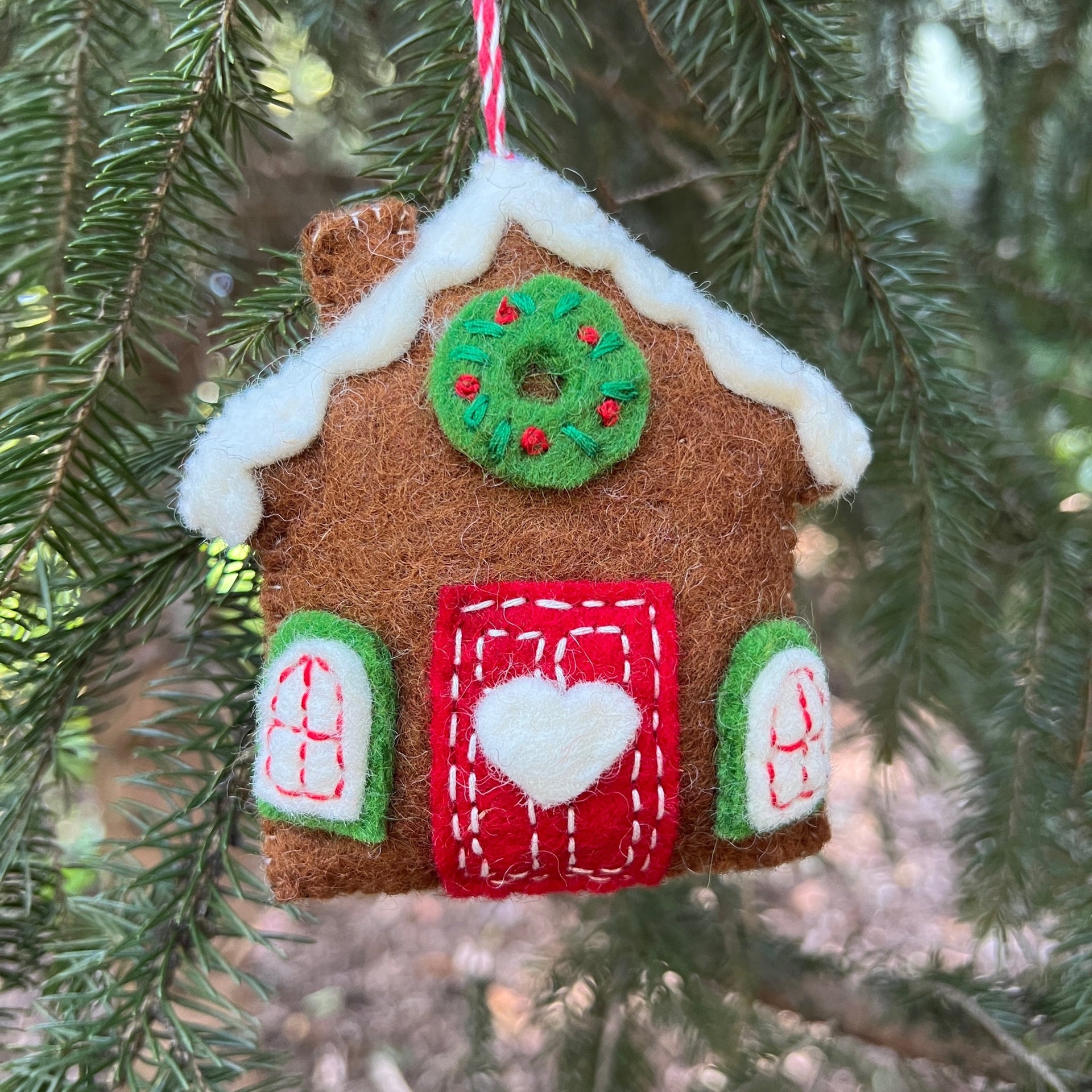 cute felt gingerbread house ornament hanging on evergreen tree