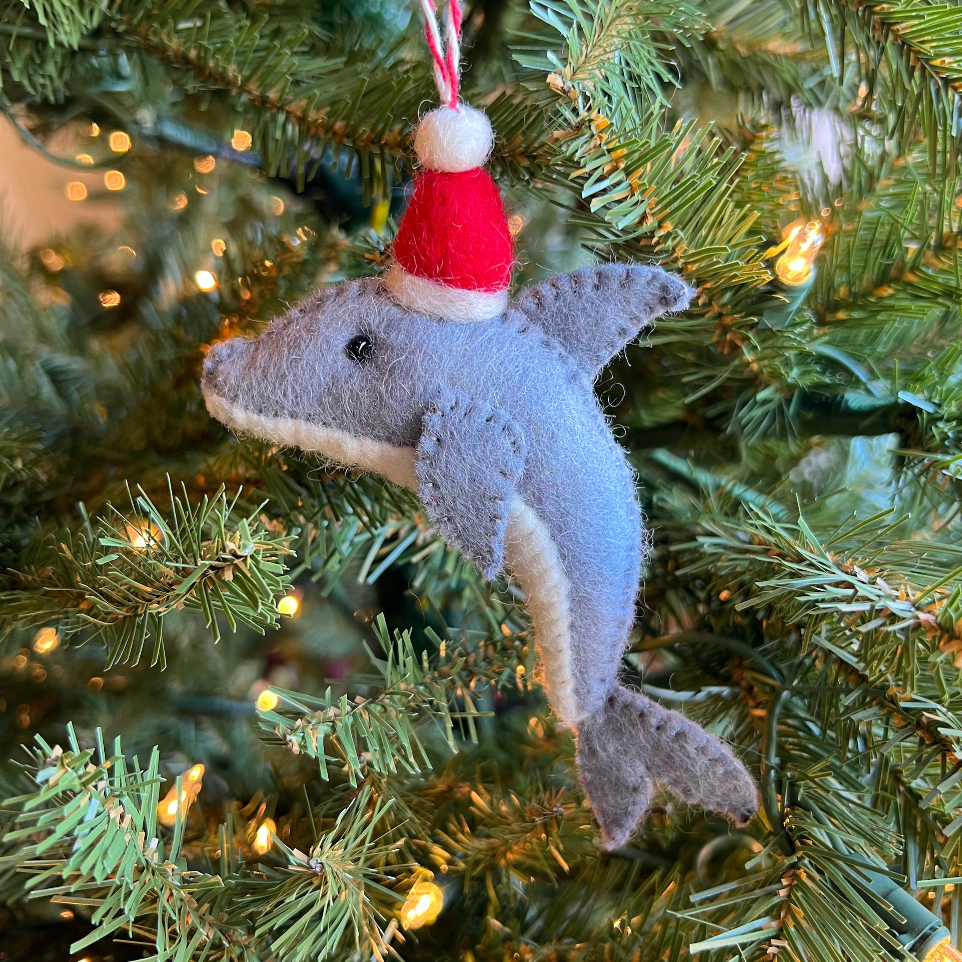 Felt dolphin santa ornament hanging on Christmas tree