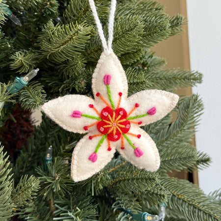 Decorative embroidered wool flower ornament hanging on a Christmas tree