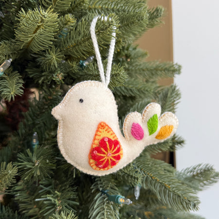white wool dove ornament hanging on a Christmas tree