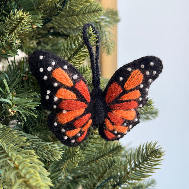 Monarch Butterfly ornament with orange and black wings on a green christmas tree
