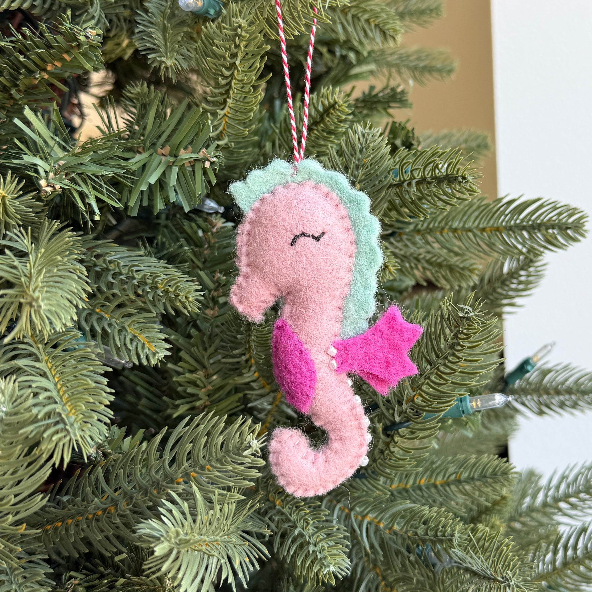 Pink seahorse ornament hanging on a Christmas tree