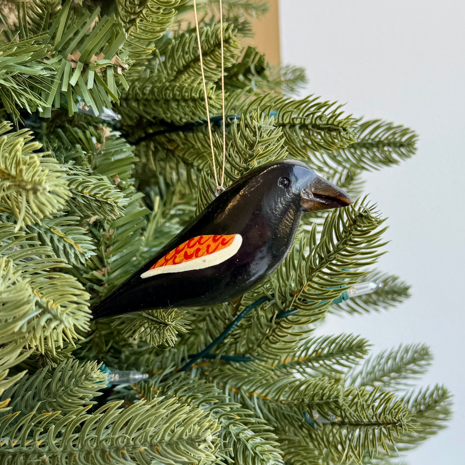 red winged black bird ornament hanging on a Christmas tree