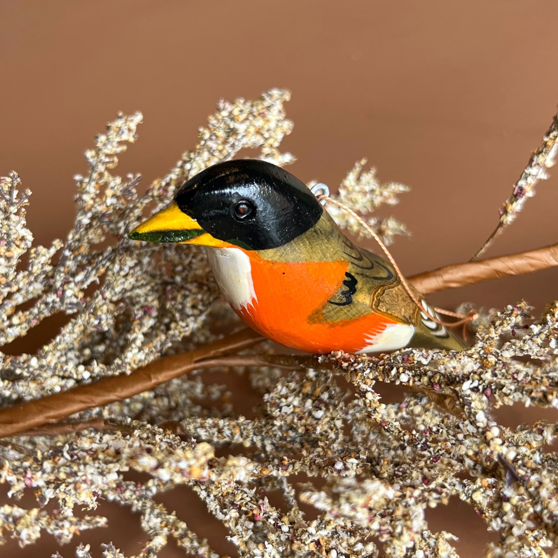 Colorful bird figurine on a branch with a brown background