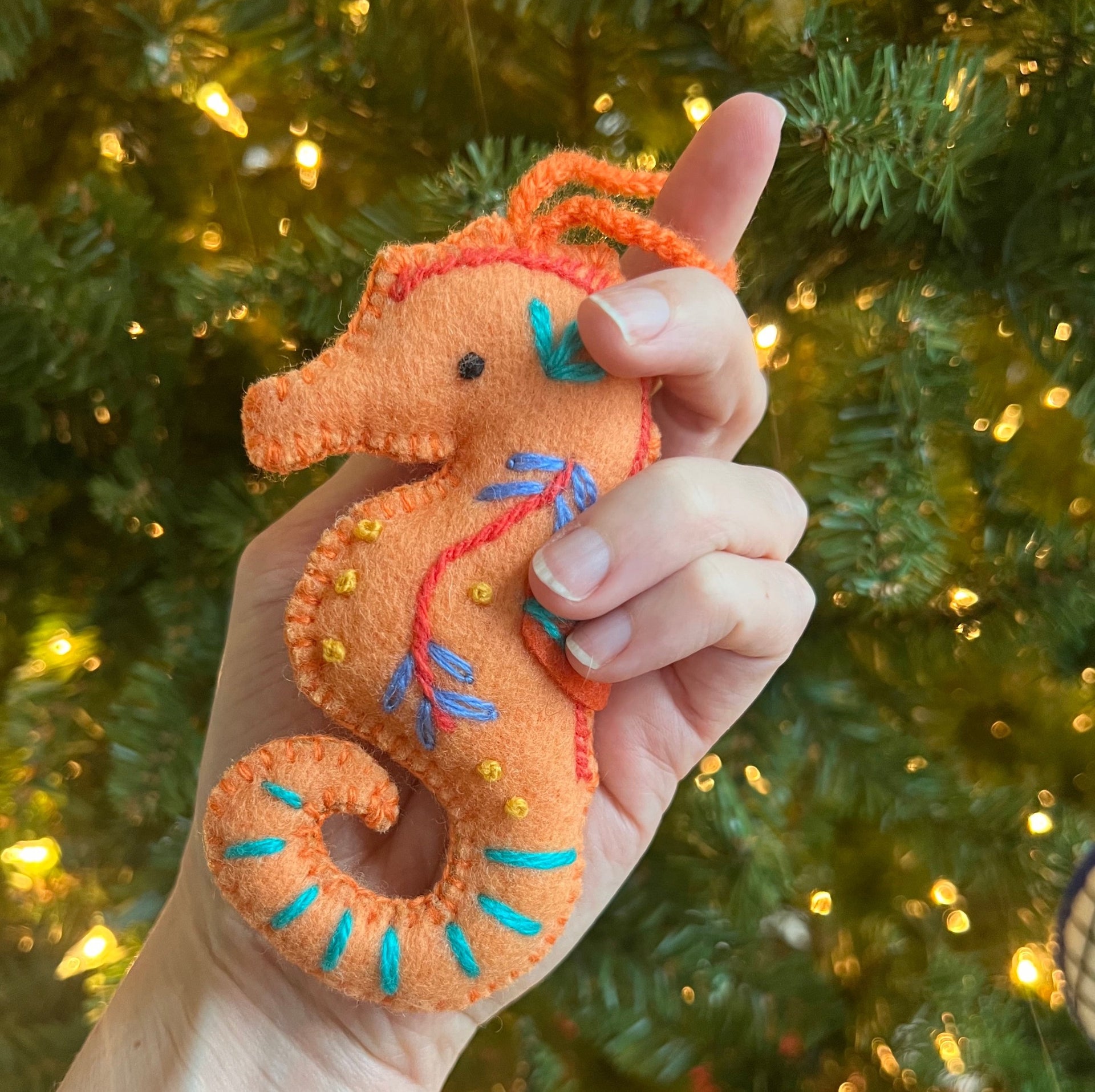 Handmade seahorse christmas ornament being help by the tree