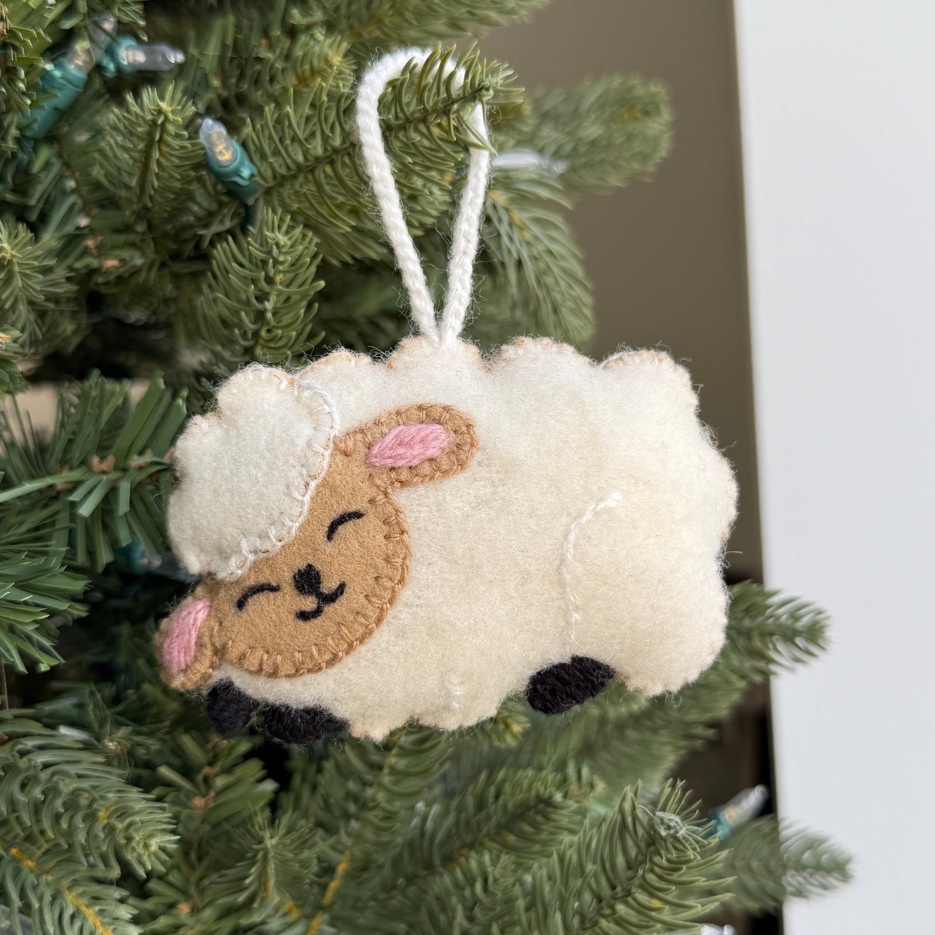 Sheep-shaped wool Christmas ornament hanging on a tree