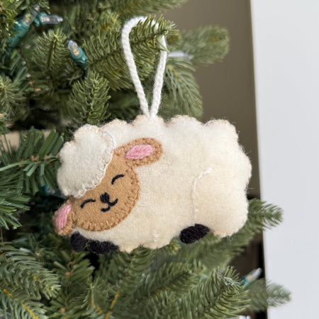 Sheep-shaped wool Christmas ornament hanging on a tree