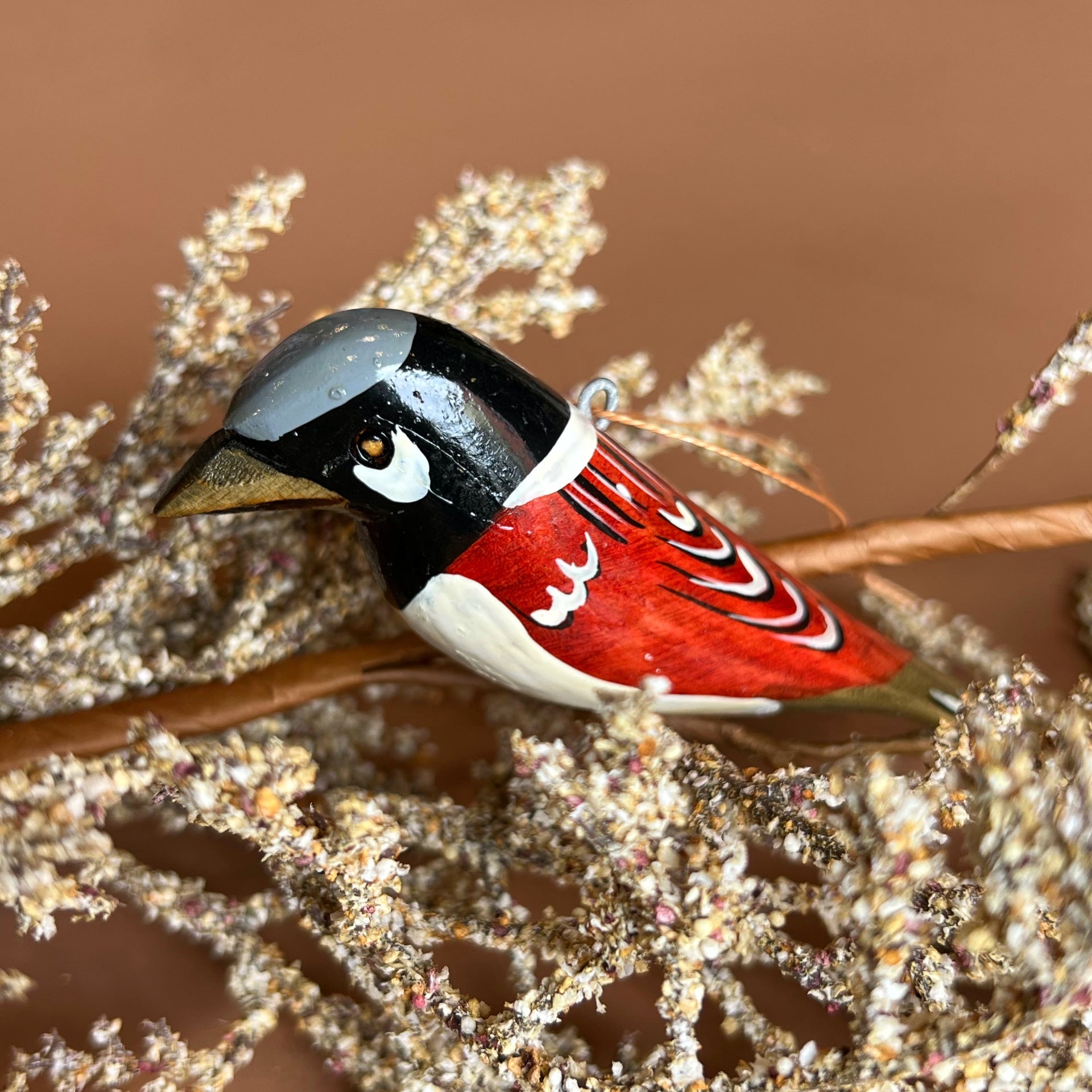 Decorative bird ornament on a branch with a brown background