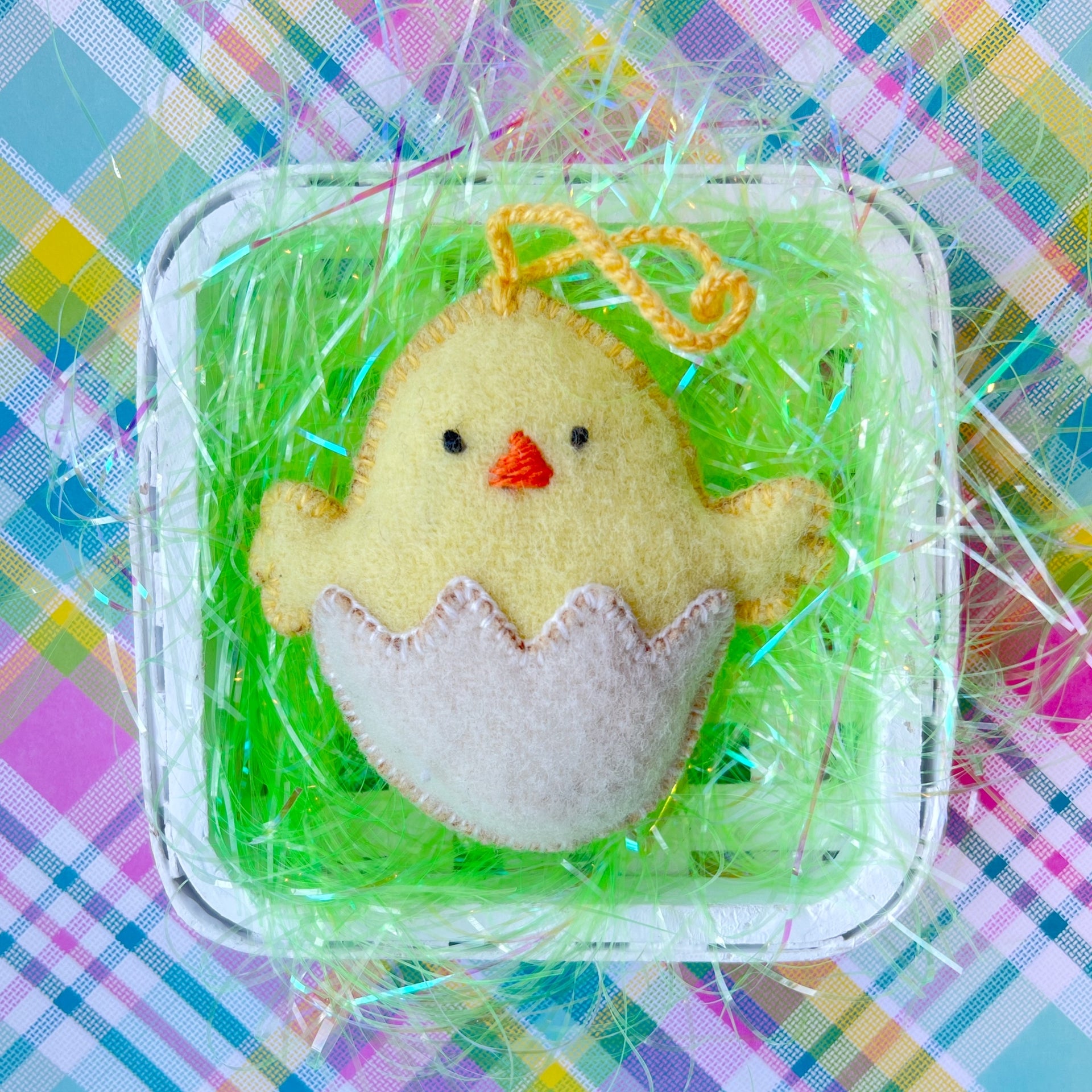 Baby chick Easter ornament resting in a basket of grass.
