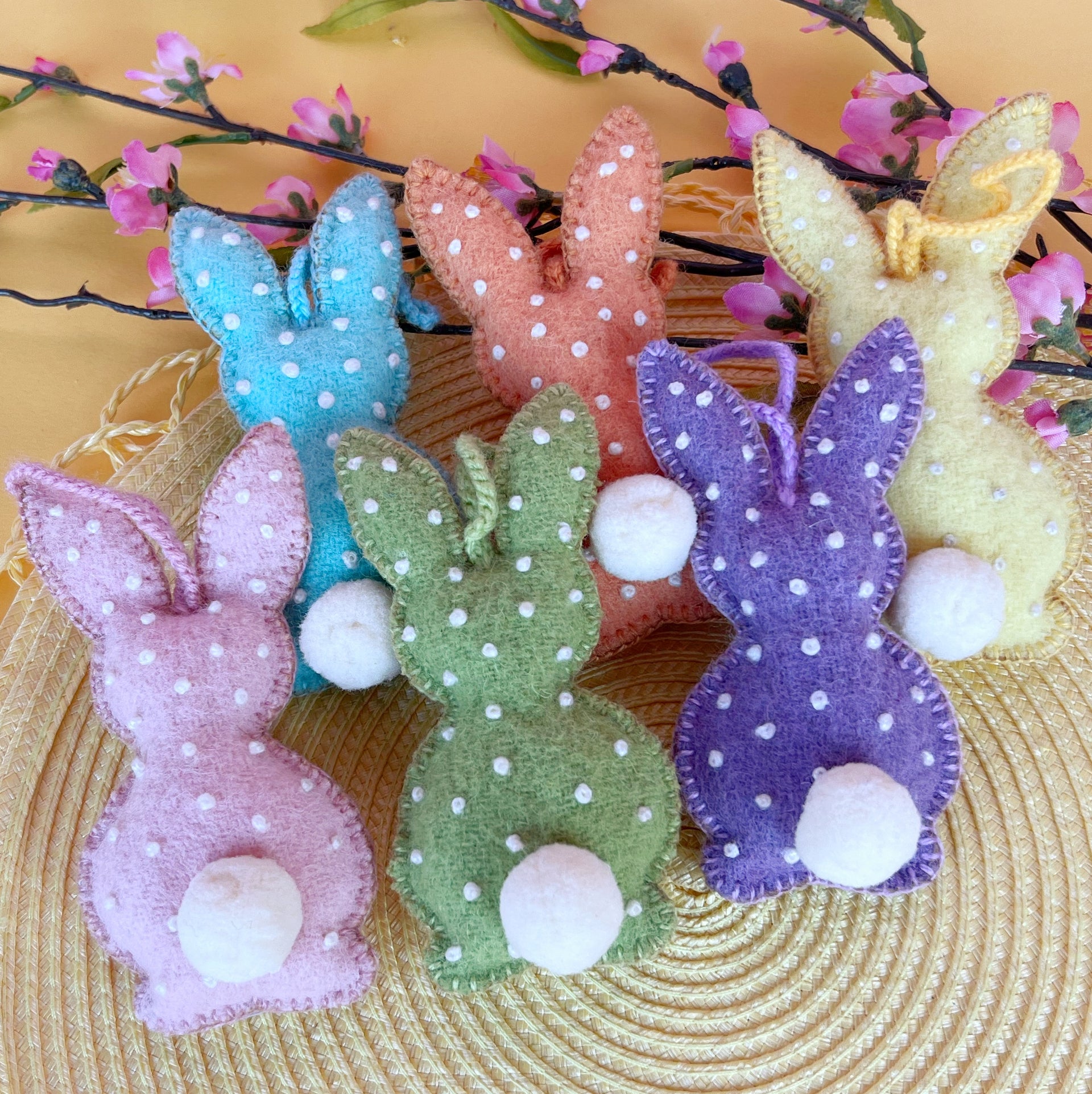 Six handmade Easter bunny Ornaments in soft pastel colors with embroidered dots.
