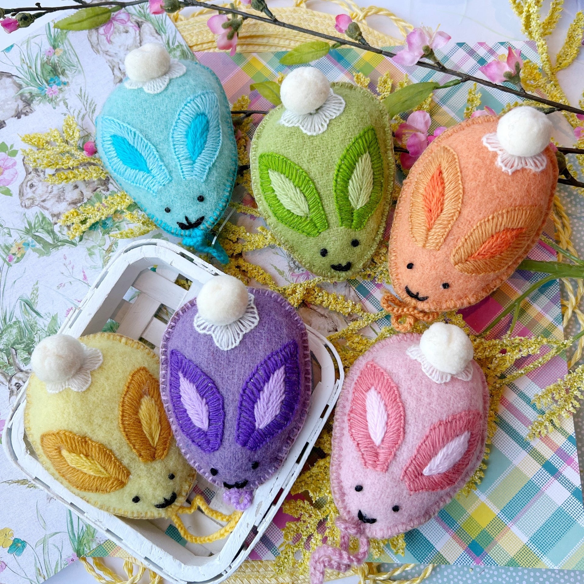 Colorful pastel bunny egg Easter ornaments styled together on spring background.