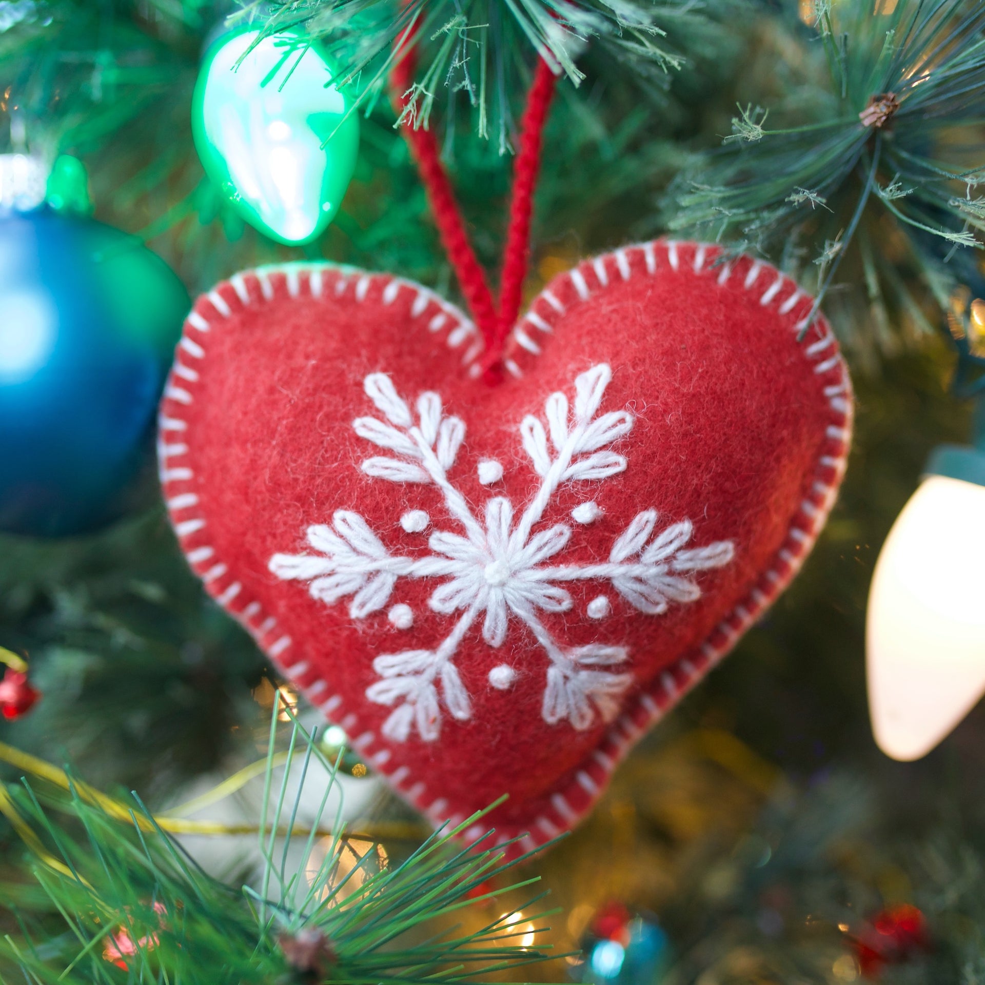 Classic soft wool red embroidered heart ornament hanging on a Christmas tree