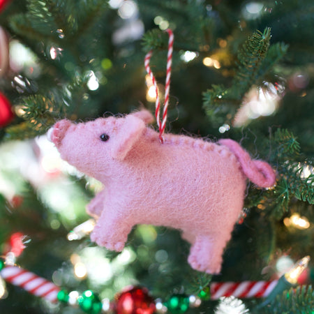 Felt pink pig ornament hanging on a christmas tree