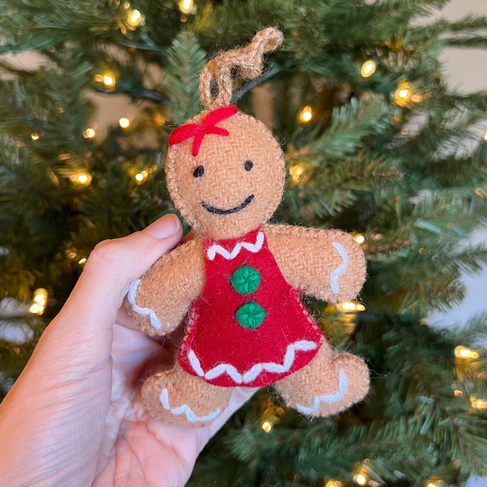 Holding a plush handmade Gingerbread Woman Ornament in from of Christmas Tree