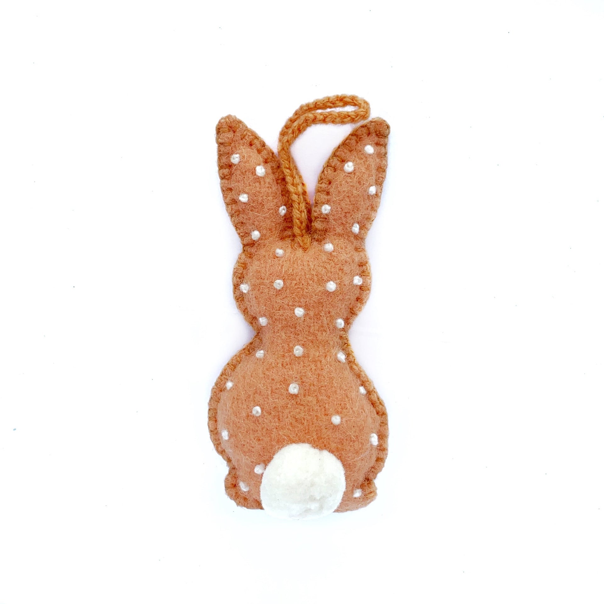 Pastel orange handmade Easter bunny ornament with embroidered white dots and pom pom tail.