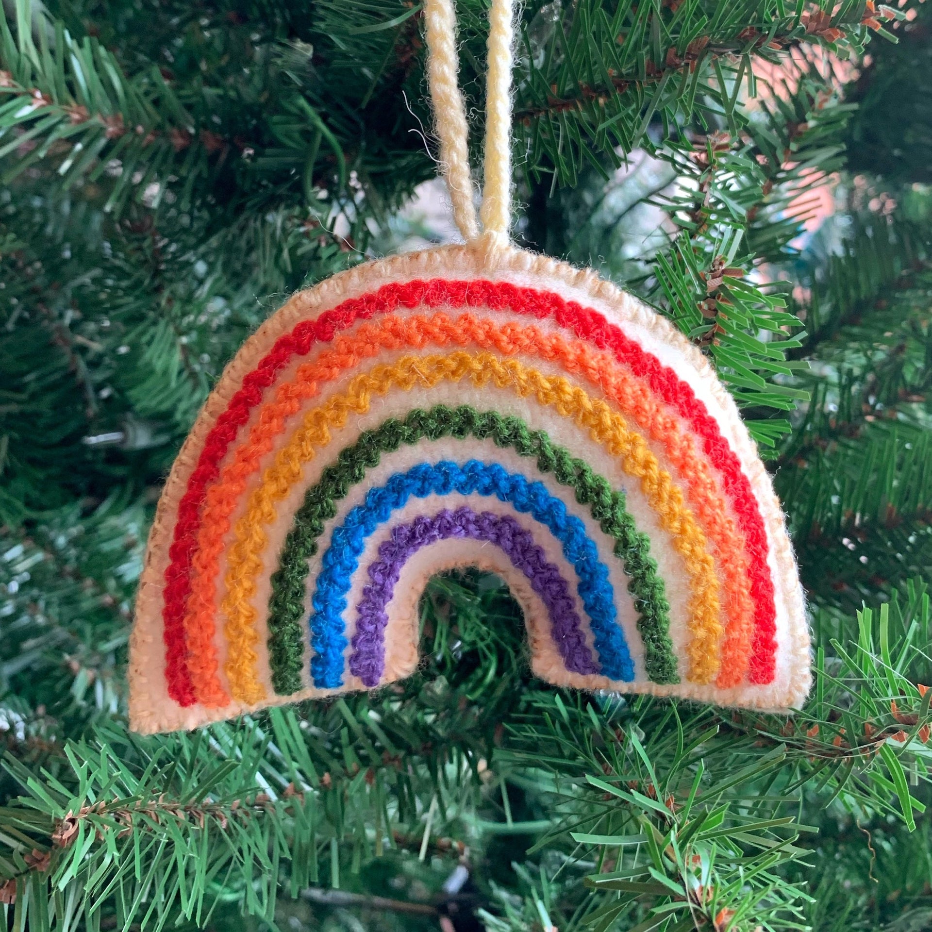 Handmade rainbow ornament hanging on Christmas tree.