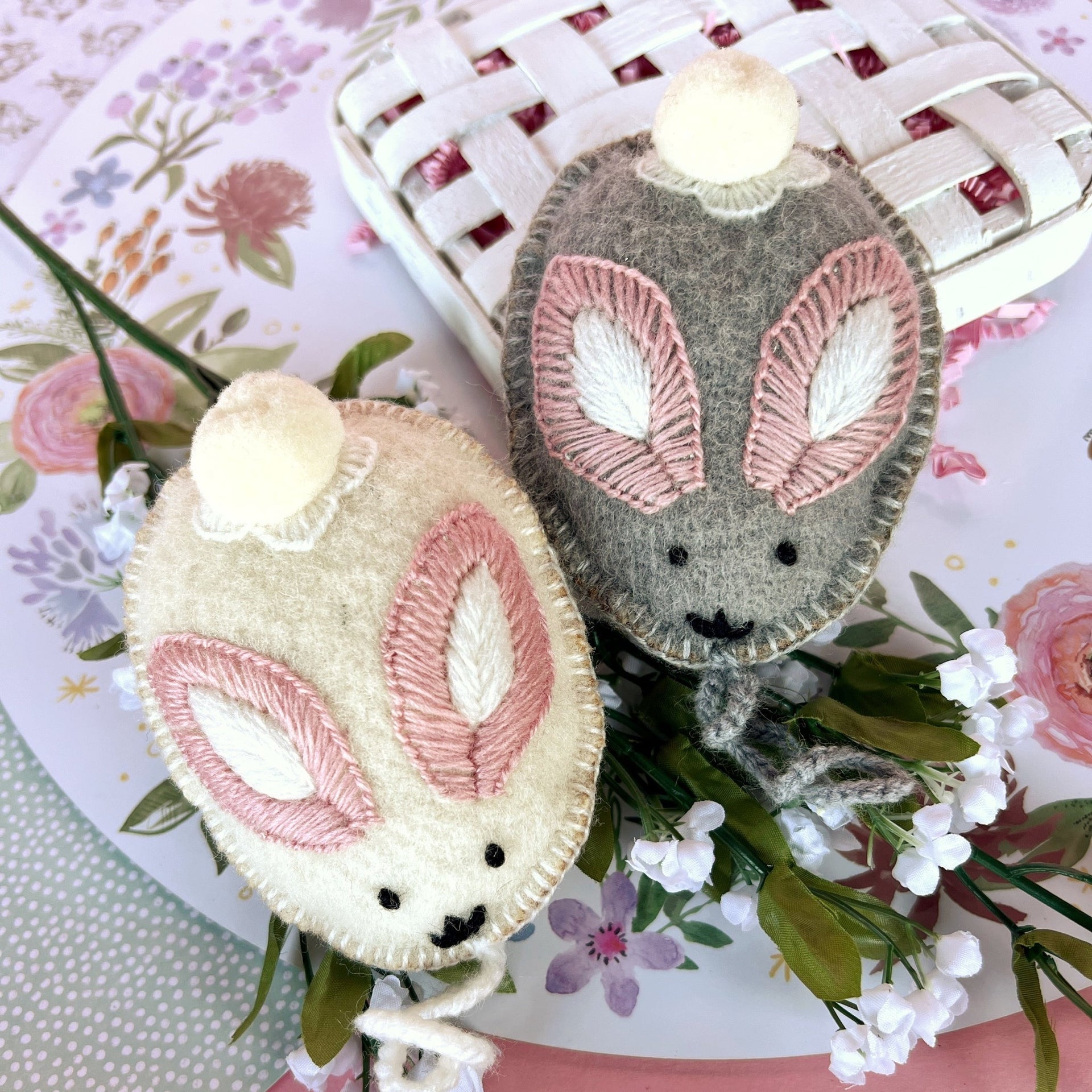 Gray and White Bunny Egg Easter Ornaments resting on flowers.